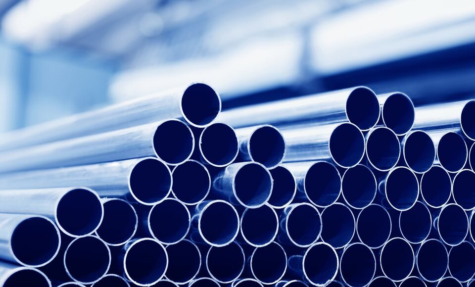 Steel tubes against industrial blurred background.